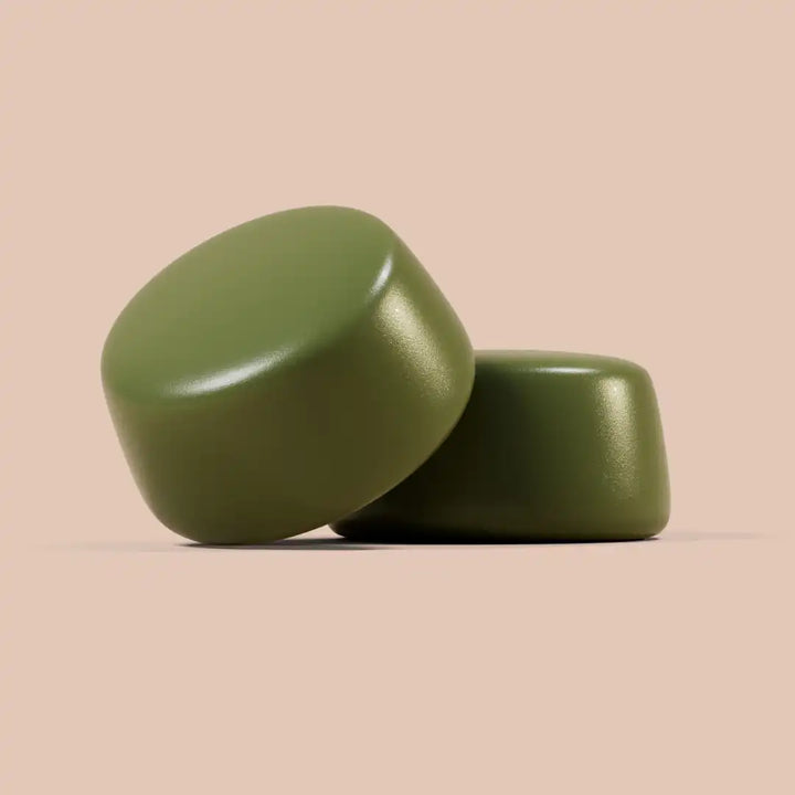 Two green cylindrical gummies on a beige background