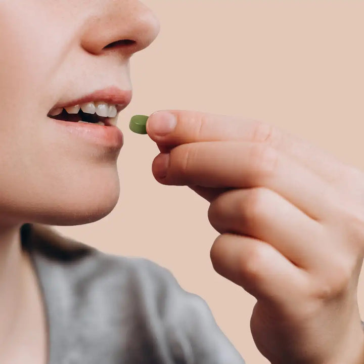 Person about to take a green gummie with a neutral background
