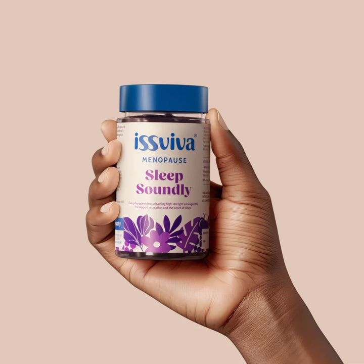 Hand holding a bottle of issviva Sleep Soundly supplement on a beige background